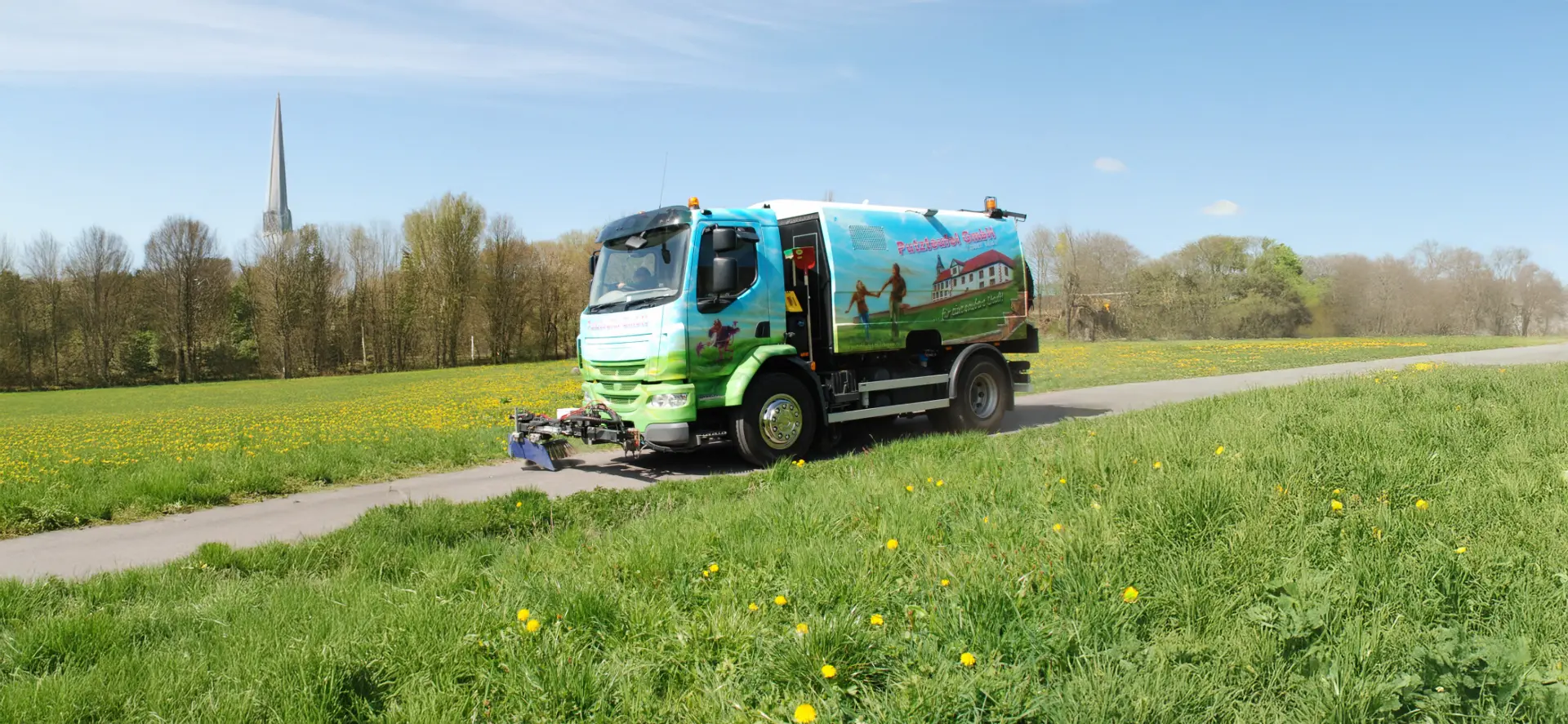 Kehrmaschine der Putzteufel GmbH reinigt eine Landstraße in Schmalkalden bei sonnigem Wetter.
