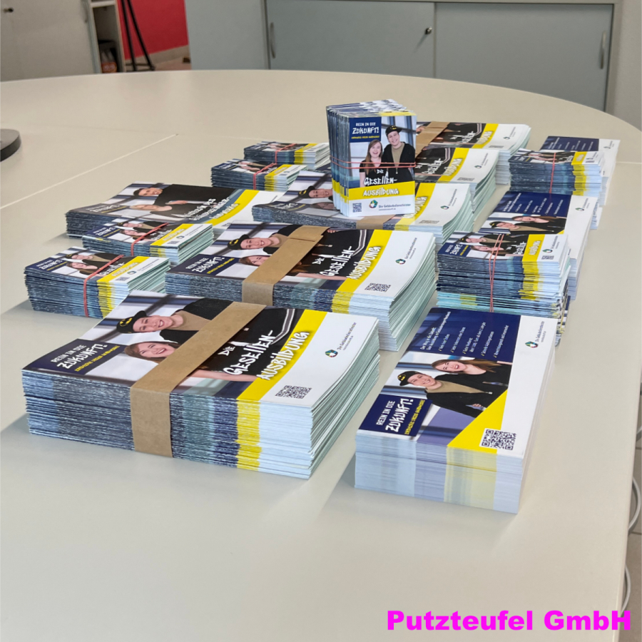 Gestapelte Ausbildungsflyer der Putzteufel GmbH auf Tisch, Informationsmaterial für Karriere und Ausbildung.