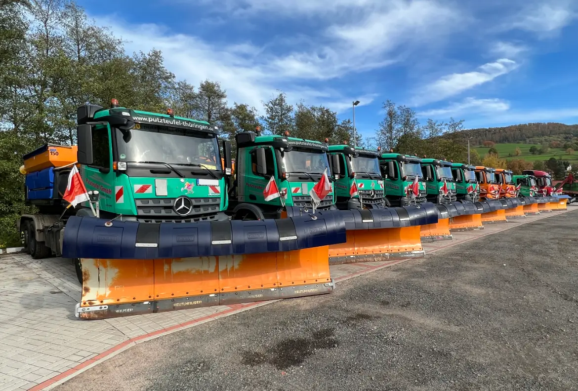 Reihe von Winterdienst-Lkw mit Schneepflügen bereit für den Einsatz bei Schnee und Eis.